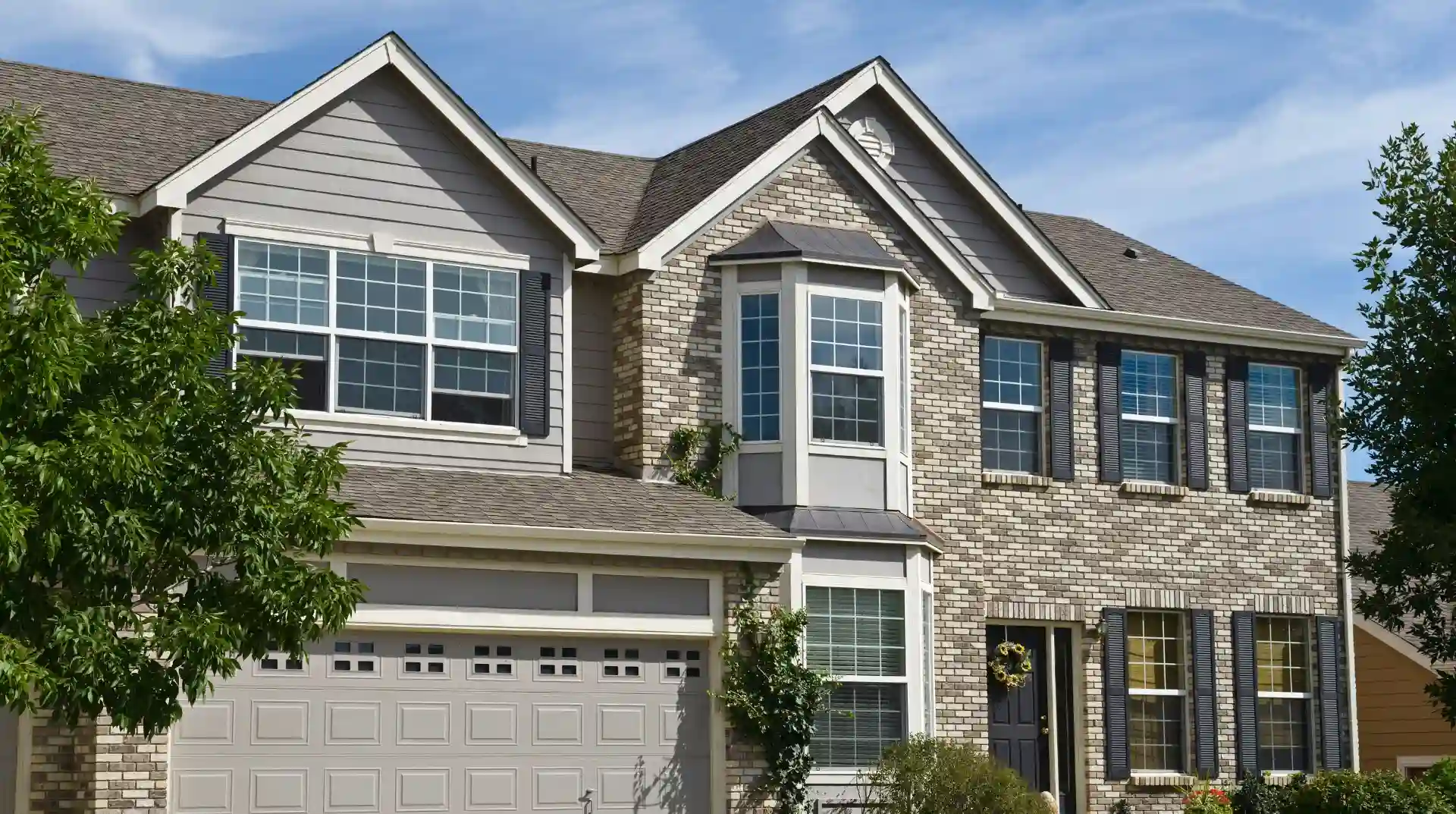 Casa familiar de dos pisos con fachada de ladrillo y techo gris.