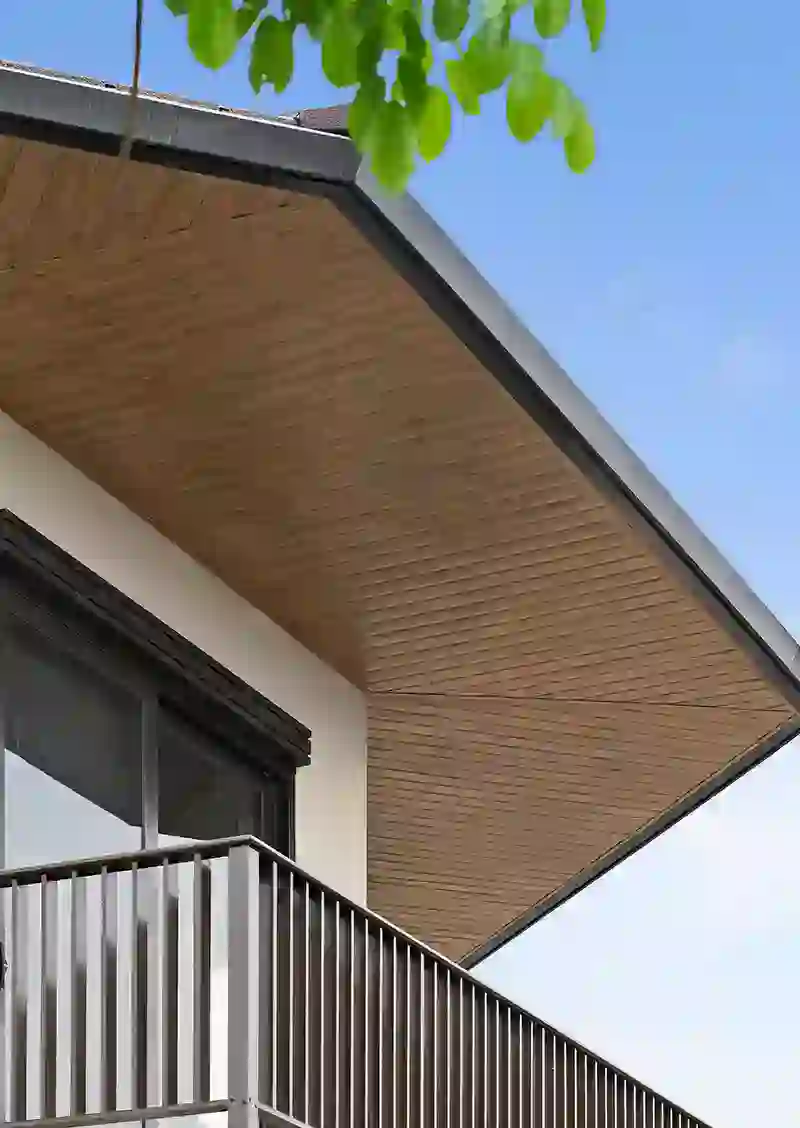 Detalle de techo de madera y balcón con barandilla metálica.