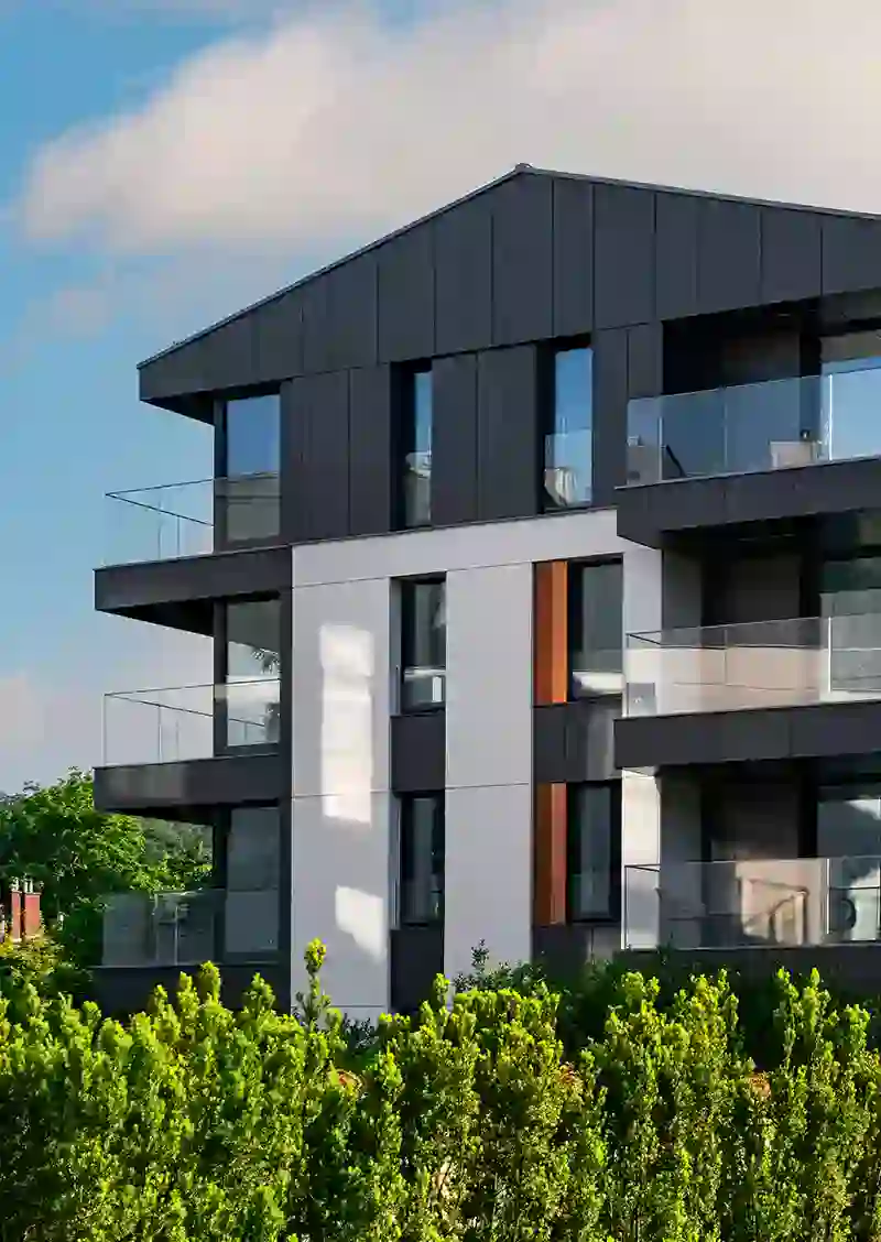 Edificio de apartamentos moderno con fachada negra y balcones de vidrio.
