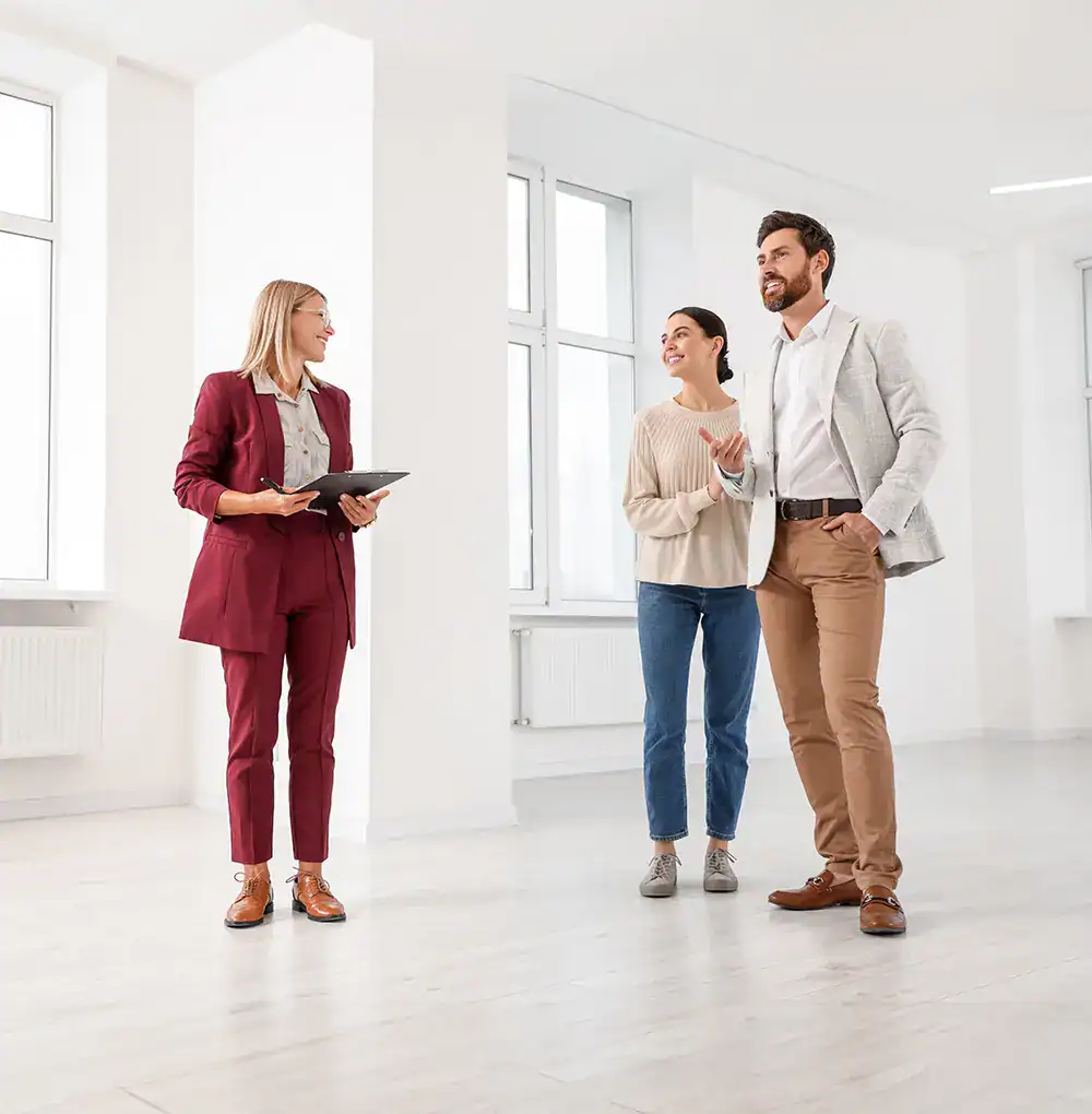 Agente inmobiliario mostrando propiedad a pareja interesada en comprar casa.